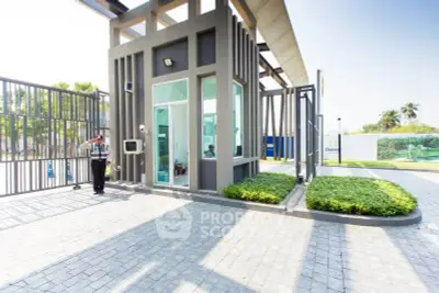 Modern gated entrance with security booth and landscaped surroundings.
