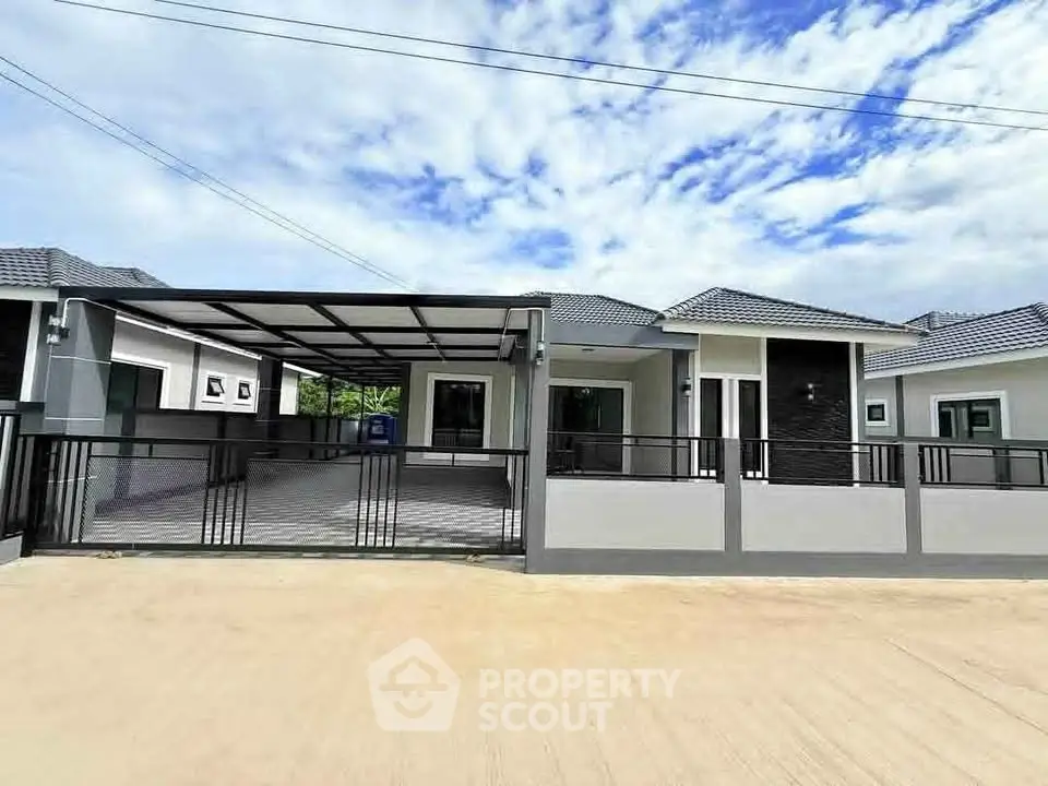 Modern single-story house with spacious driveway and sleek design under a clear blue sky.