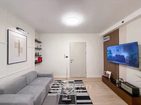 Modern living room with sleek design, featuring a large TV, stylish sofa, and contemporary decor.