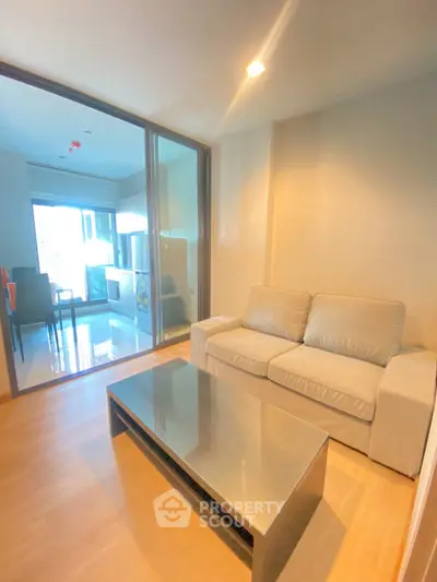 Modern living room with cozy sofa and sleek coffee table, adjacent to a bright kitchen area.