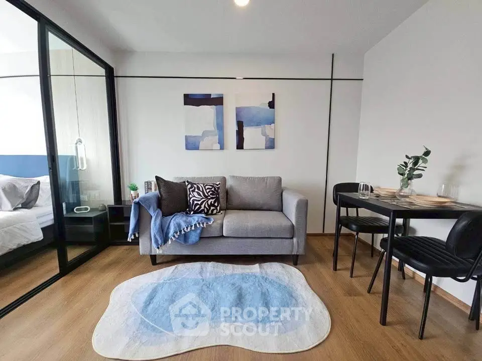 Modern living room with stylish decor and glass partition leading to bedroom