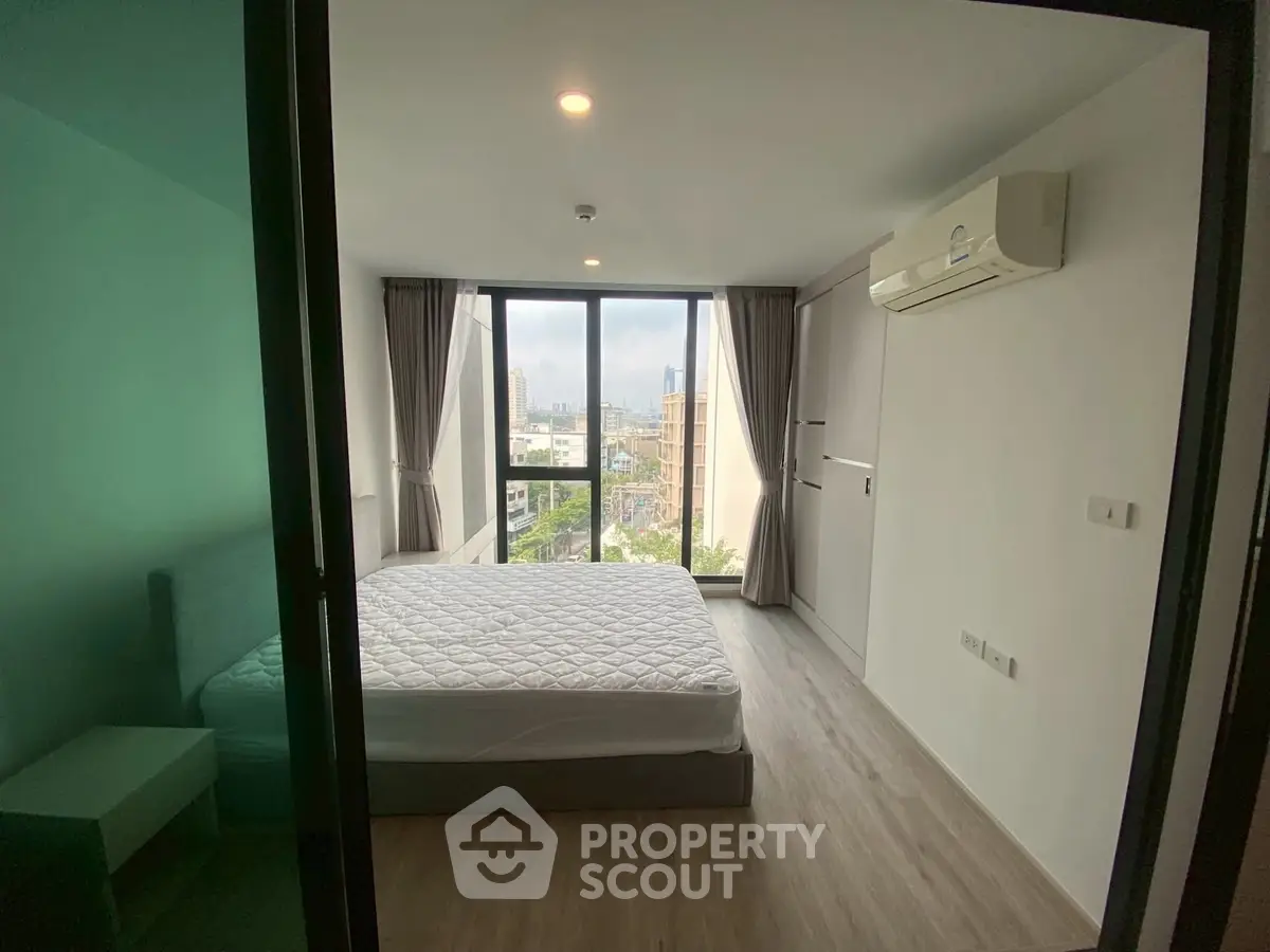 Modern bedroom with large windows and city view, featuring minimalist design and air conditioning.