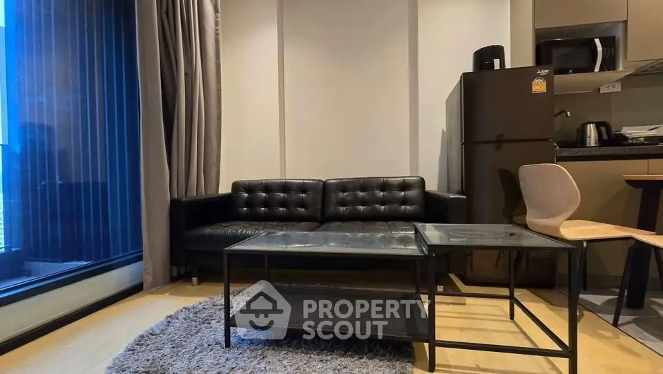 Modern living room with sleek black sofa and kitchen area, perfect for urban living.