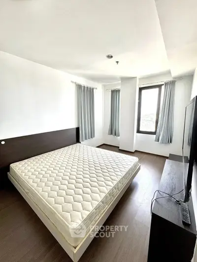 Spacious bedroom with large windows and modern furnishings in a bright apartment.