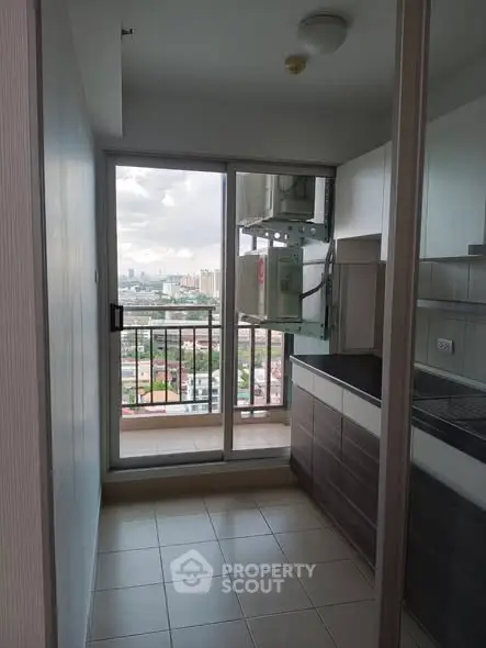 Modern kitchen with balcony and city view, featuring sleek cabinetry and tiled flooring.