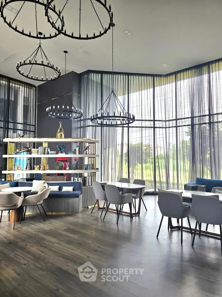 Luxurious modern library with floor-to-ceiling windows and elegant chandeliers in a high-end building.