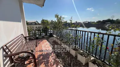 Charming balcony with serene water view and lush greenery, perfect for relaxation.