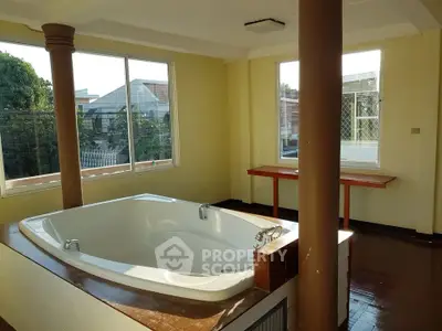 Spacious room with built-in bathtub and large windows offering natural light and outdoor views.