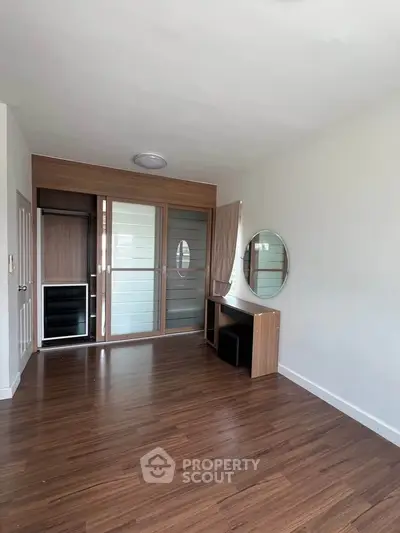 Spacious room with wooden flooring and modern sliding wardrobe