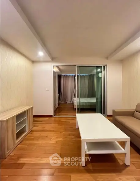 Spacious living room with wooden flooring and modern furniture in a stylish apartment.