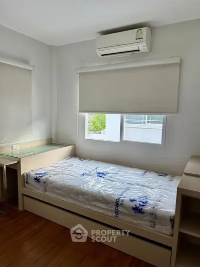 Cozy bedroom with single bed and air conditioning, featuring modern minimalist design and natural light.