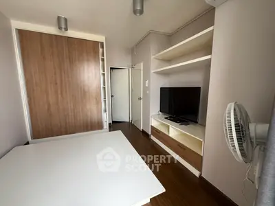 Modern bedroom with built-in wardrobe and TV unit, featuring sleek wooden flooring.