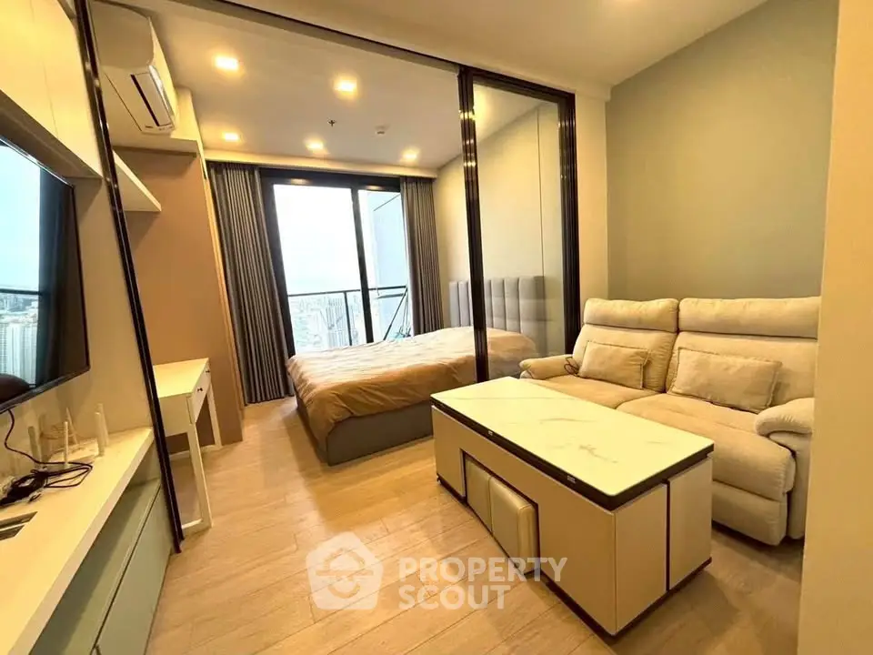 Modern studio apartment with cozy living area and bedroom, featuring a sleek design and city view.