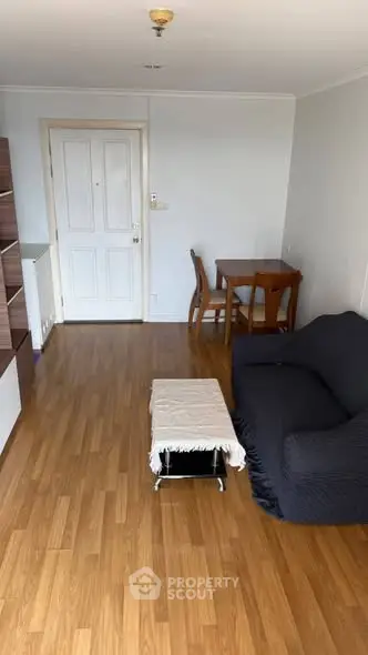 Cozy living room with wooden flooring, sofa, and dining table in a modern apartment.