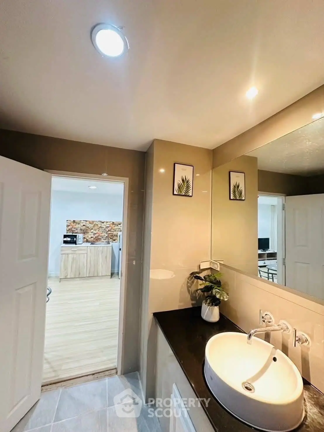 Modern bathroom with sleek sink and view into stylish kitchen