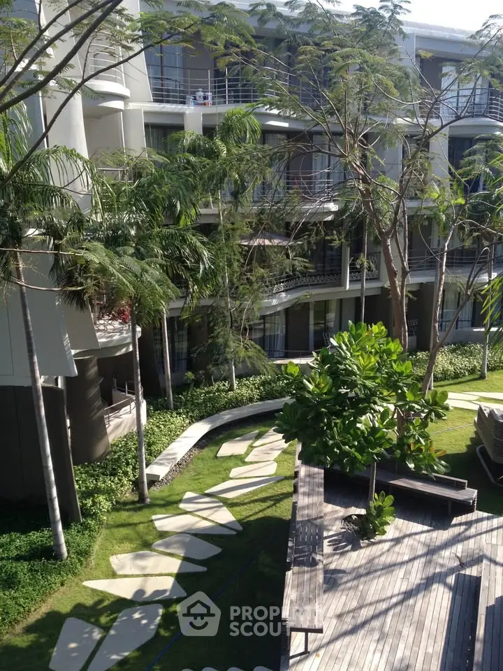 Modern apartment building with lush garden and outdoor seating area, perfect for relaxation.