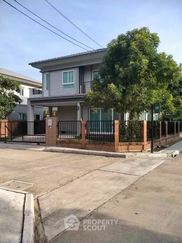 Modern two-story house with fenced yard and lush greenery
