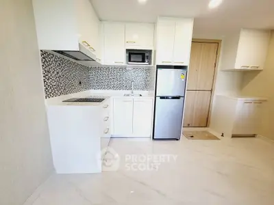 Modern kitchen with sleek white cabinets and mosaic backsplash in a bright apartment.