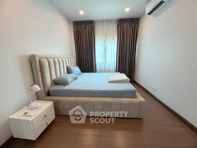 Modern bedroom with plush bed, elegant curtains, and sleek air conditioning unit.