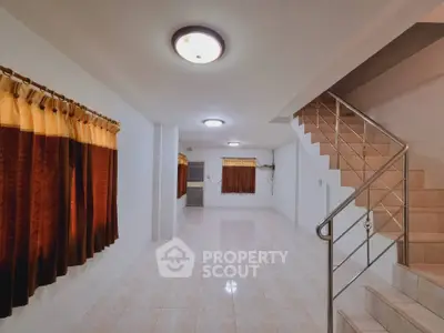Spacious tiled living area with staircase and warm lighting, ideal for family gatherings.