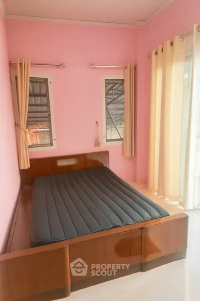 Cozy bedroom with pink walls and large windows for natural light.