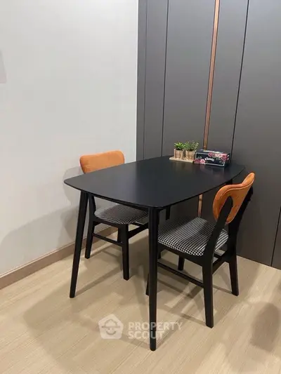 Modern dining area with sleek black table and stylish chairs in a contemporary setting.