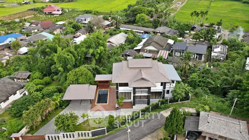 Stunning aerial view of a modern house with lush greenery and scenic surroundings, perfect for serene living.