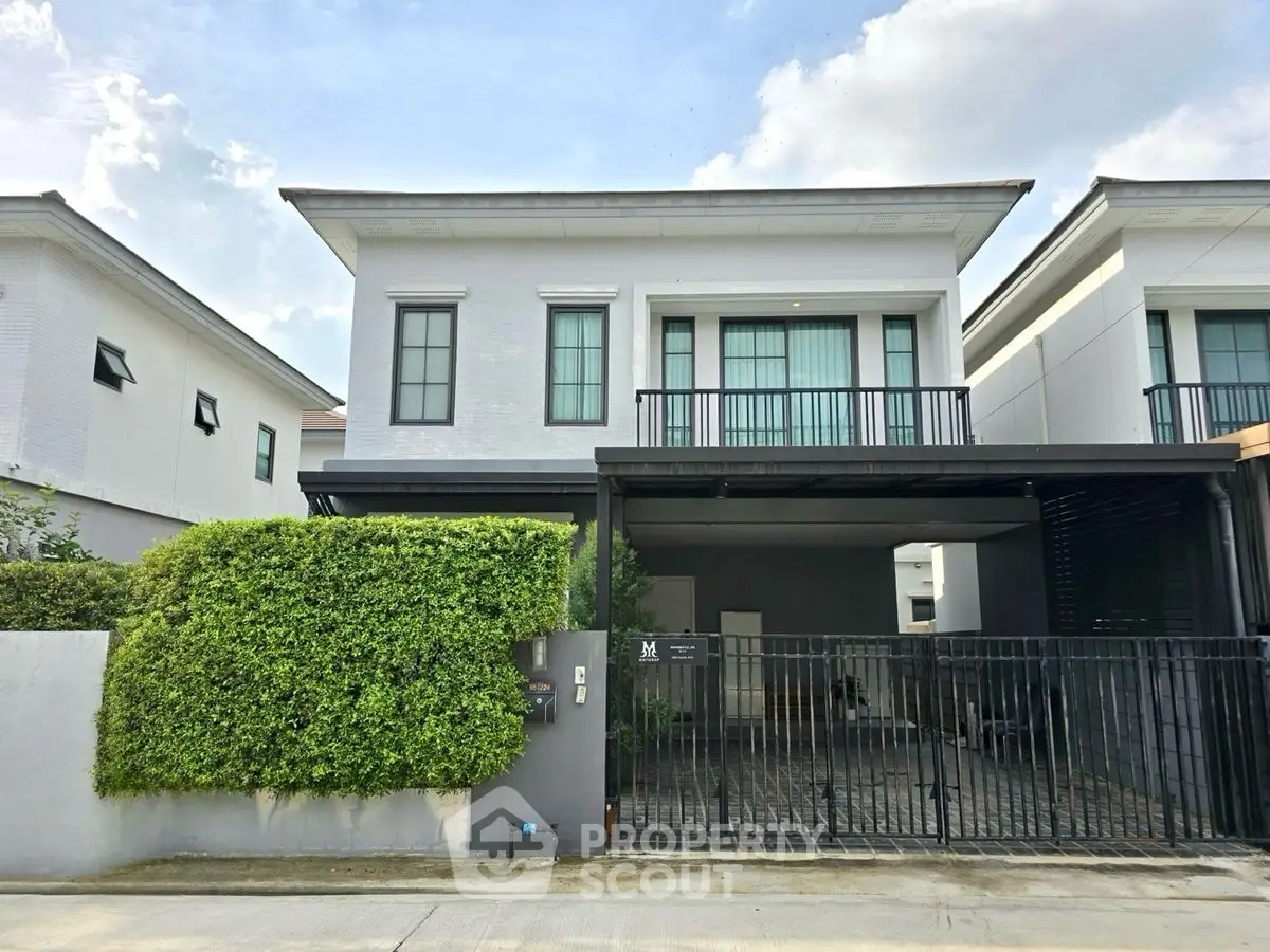 Modern two-story house with gated driveway and lush greenery