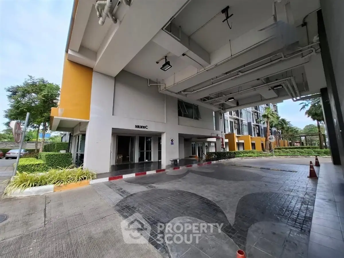 Modern building entrance with covered driveway and landscaped surroundings.