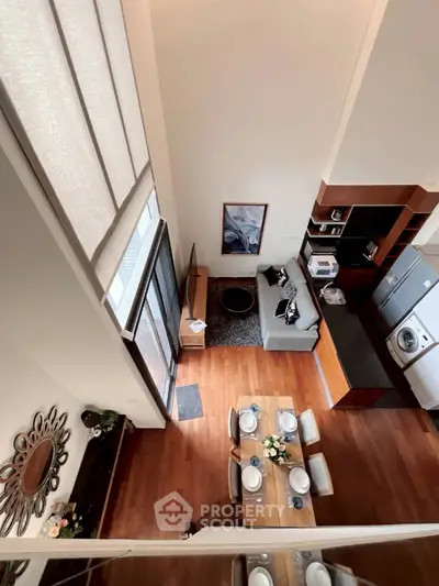 Spacious open-plan living room with modern kitchen and dining area, featuring high ceilings and stylish decor.