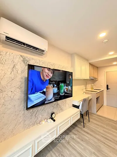 Modern living room with wall-mounted TV and compact kitchen in stylish apartment.