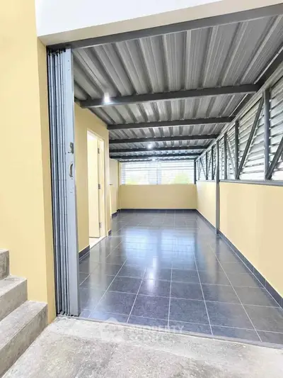 Spacious covered balcony with modern metal roofing and tiled flooring, perfect for outdoor relaxation.