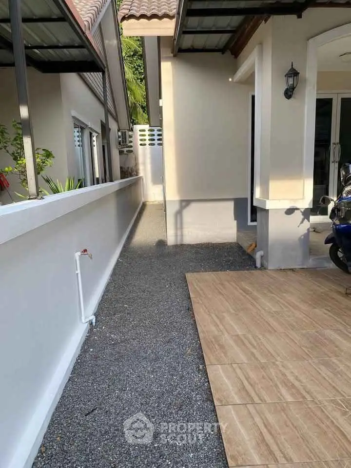 Charming exterior walkway with tiled and gravel path beside modern home