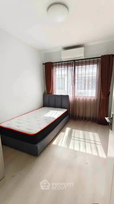 Bright bedroom with single bed, large window, and air conditioning in modern apartment.