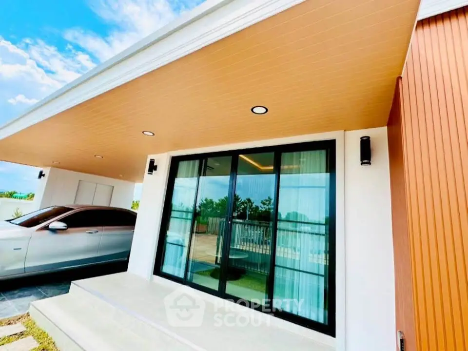 Modern house exterior with sleek design and luxury car parked in driveway.