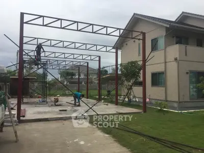 Construction site of a modern house with steel framework and lush green lawn.