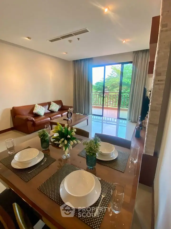 Spacious living room with elegant dining area and large windows overlooking greenery.