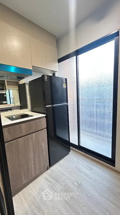 Modern kitchen with sleek black fridge and frosted glass window