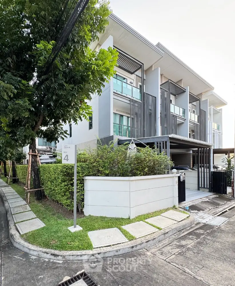 Modern townhouse with sleek design and lush greenery in a serene neighborhood corner.