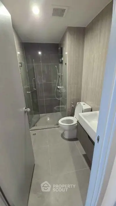 Modern bathroom with glass shower, sleek fixtures, and neutral tiles.
