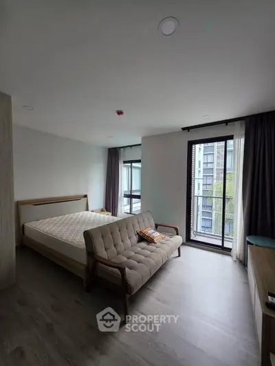 Spacious bedroom with modern decor and large windows offering natural light and city views.