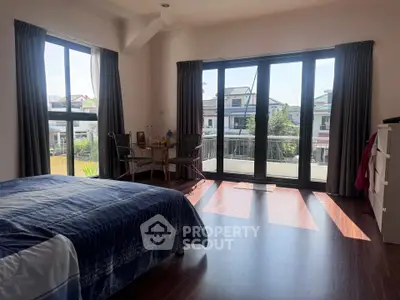 Spacious bedroom with large windows and balcony access, offering natural light and a serene view.