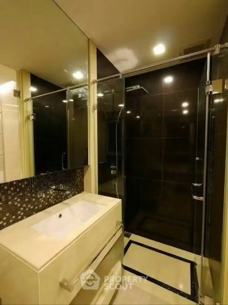 Modern bathroom with sleek glass shower and stylish vanity in contemporary apartment.