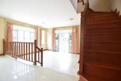 Spacious living room with wooden staircase and large windows for natural light.