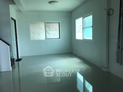 Spacious empty room with glossy tiled floor and large windows, ideal for customization.