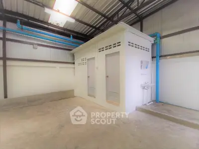 Industrial warehouse interior with restroom facilities and exposed piping.