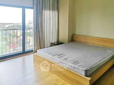 Spacious bedroom with large window offering stunning city views in modern apartment.