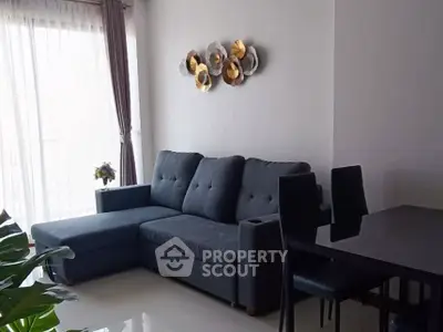 Modern living room with stylish sofa and dining area, featuring elegant wall decor and natural light.