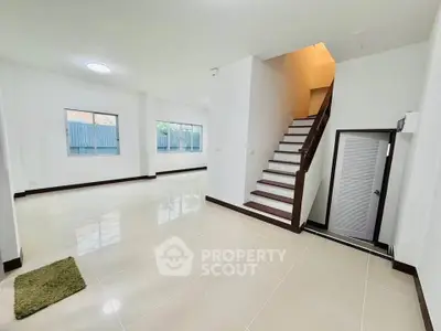 Spacious modern living room with staircase and large windows in a bright, open layout.