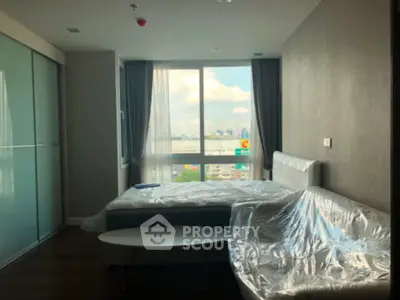 Modern bedroom with large window and city view, featuring sleek furniture and natural light.